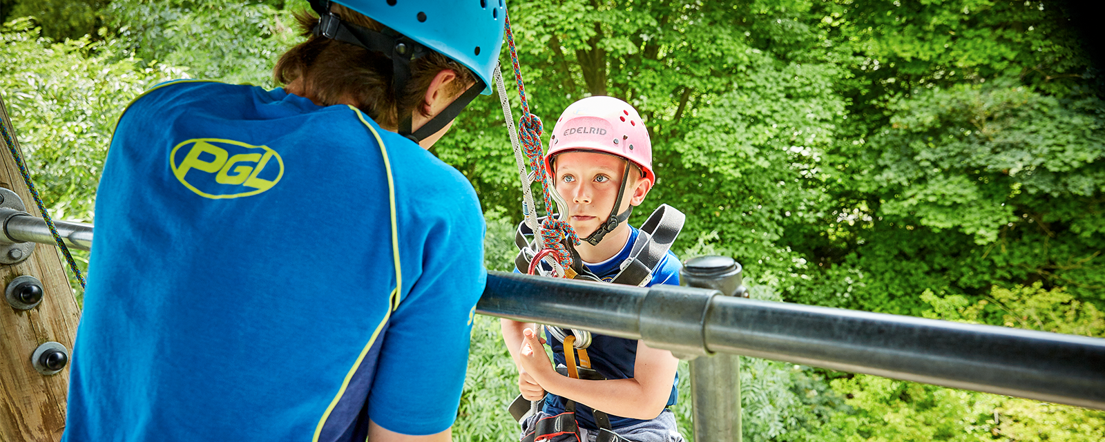 A young boy hanging of an abseil tower